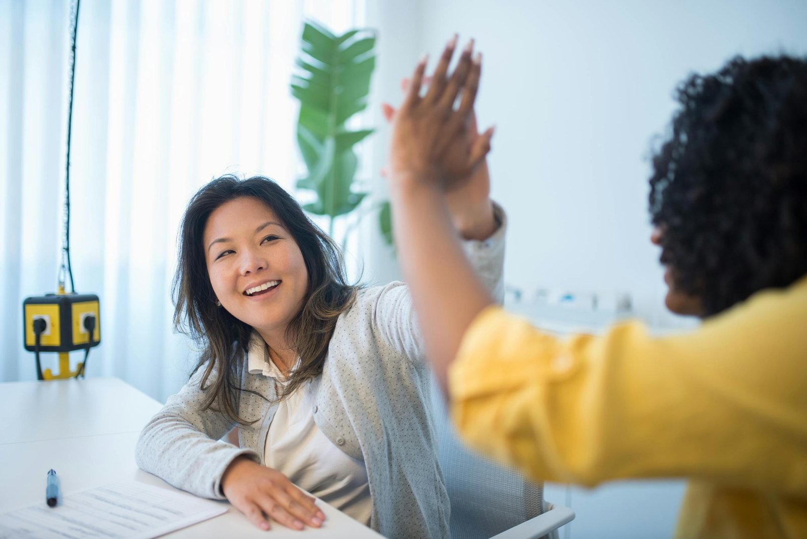 Cheerful office workers celebrating a win with a high five, showcasing teamwork and success.