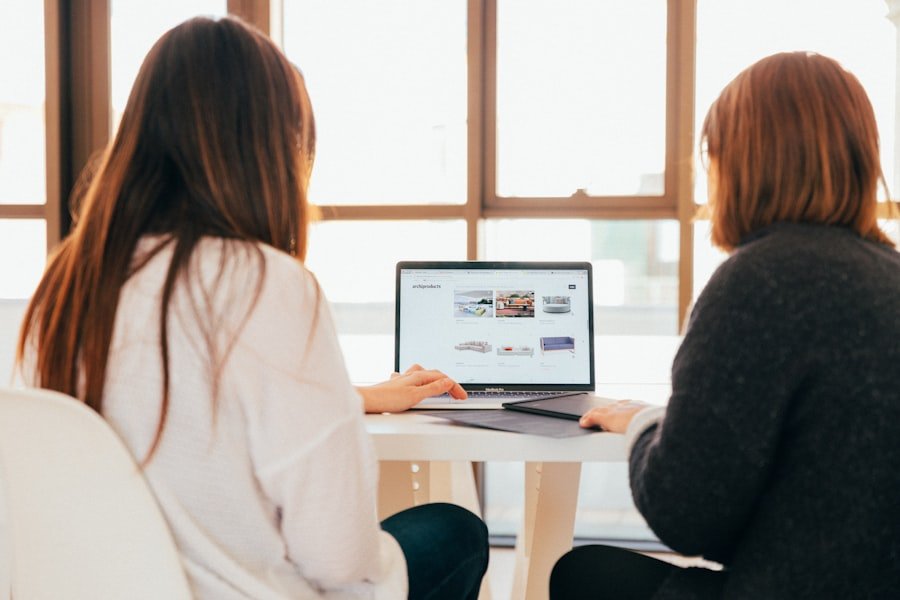 Two women facing one laptop browsing for jobs